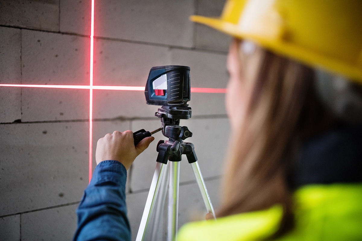 Mlada delavka z laserjem na gradbišču.
